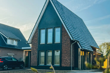 Frontansicht von zwei modernen Backsteinhäusern in den Niederlanden mit dunklen Thermory Vivid Thermo-Fichte Akzenten.