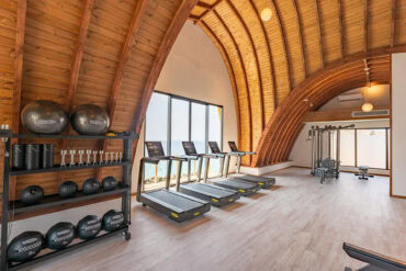 Thermory thermo-pine ceiling with arched beams in resort gym overlooking the sea.