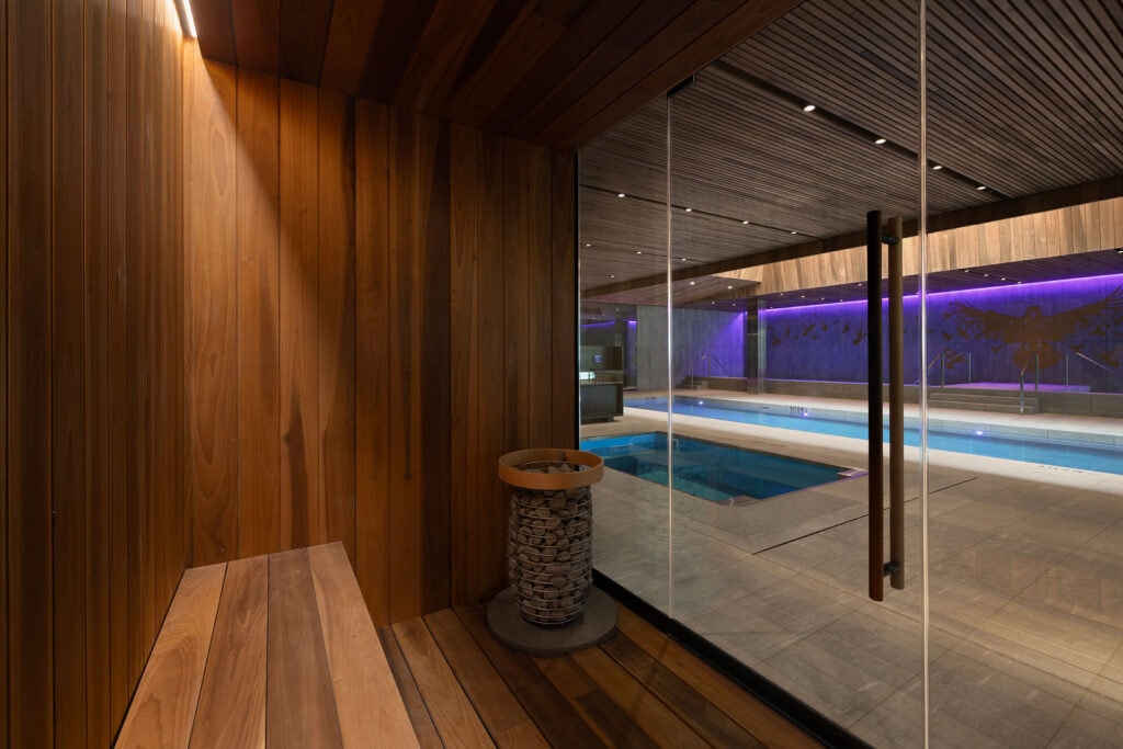 Sauna interior at the Baltimore Ravens’ Performance Center with Thermory Thermo-Magnolia benches and wall panels overlooking the hydrotherapy pool.