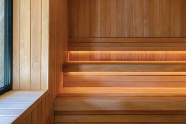 Close-up of Thermory alder sauna benches and wall panels with natural grain and soft light detailing.