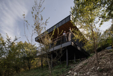 Modernes Hanghaus auf Stelzen über der Donau mit Thermory Thermo-Kiefer Terrasse und Holzdeckenverkleidung.
