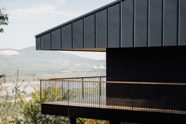 Detailansicht des Console House mit schwarzer Metallfassade und Thermory Thermo-Kiefer Terrasse über dem Tal.