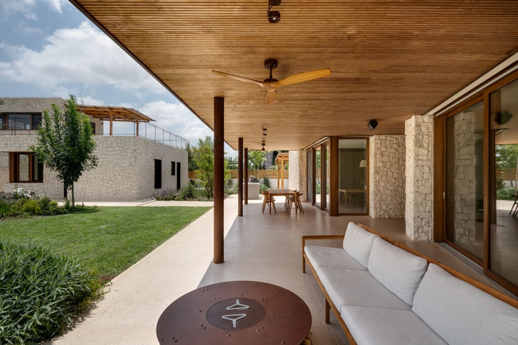 Covered outdoor terrace finished with Thermory thermo-radiata pine ceiling and cladding, opening to a stone courtyard and garden.