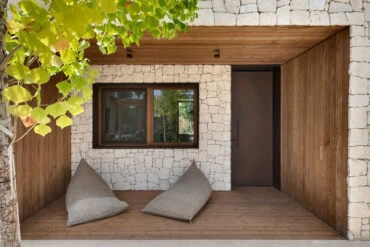 Sissepääs Thermory termotöödeldud radiata männi voodriga ja laepaneelidega, mida raamivad hele kivi ja haljastus.