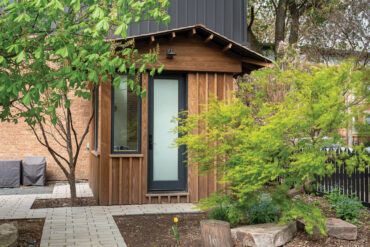 Pieni pihatoimisto, jossa Thermoryn lämpösaarniverhous, ympäröitynä vehreällä kasvillisuudella ja tiiliarkkitehtuurilla.