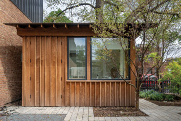 Pihatoimiston sivunäkymä pystysuuntaisella Thermory lämpösaarniverhouksella ja suurilla moderneilla ikkunoilla.