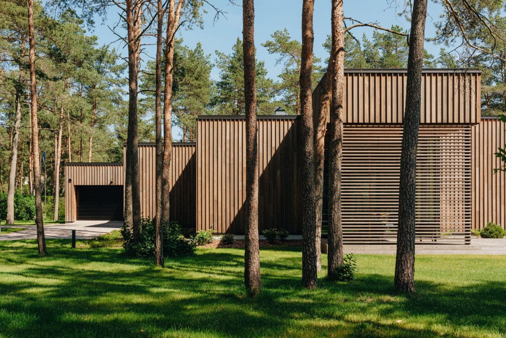 Modern house surrounded by pine trees with Thermory thermo-ash cladding and decking blending into the natural landscape.