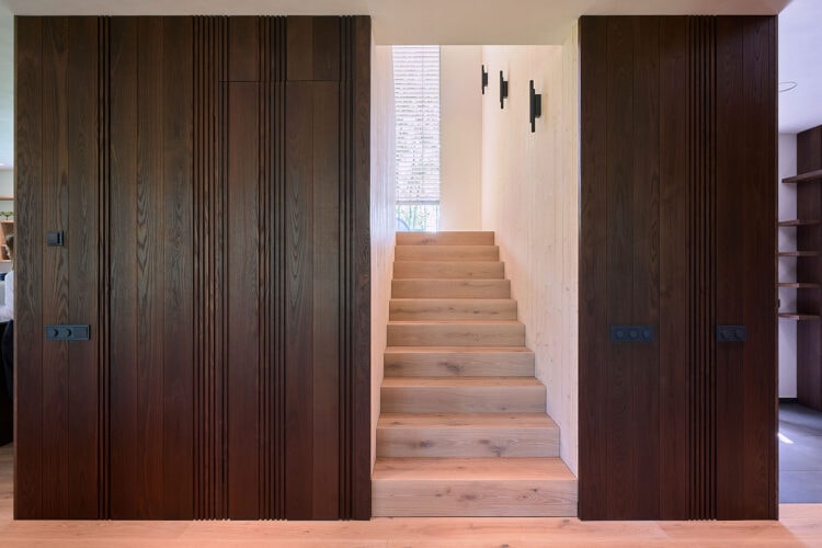 Modern hallway featuring Thermory thermo-ash wall panels in deep brown tone, creating a refined contrast and warm Nordic interior atmosphere.