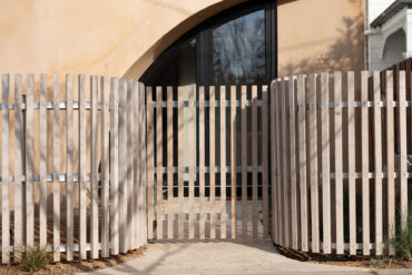 Gebogene Holzzaun- und Toranlage aus Thermory Thermo-Fichte C26 mit SIOO:X silbergrauem Finish – Teil des Maurie Novak Architekturstudios.