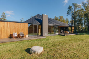 Contemporary house with Thermory thermo-hickory cladding and glass walls opening to garden.