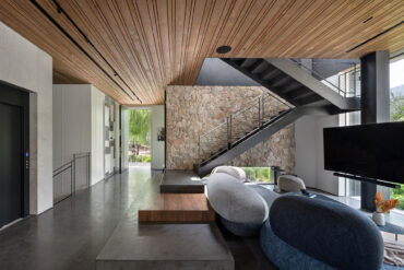 Modern interior with Thermory thermo-radiata pine ceiling, stone wall, and minimalist staircase design.