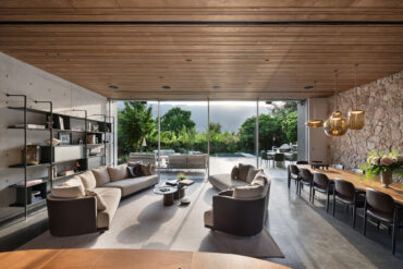 Living and dining area with Thermory thermo-radiata pine ceiling, large windows, and outdoor view.
