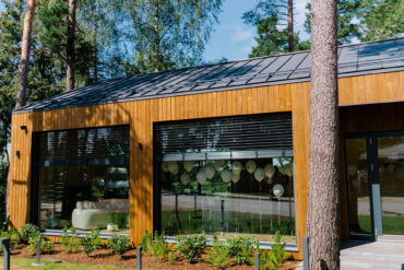 Perekodu Thermory termoradiata männi voodriga, mida ümbritsevad kõrged puud ja loomulik valgus.