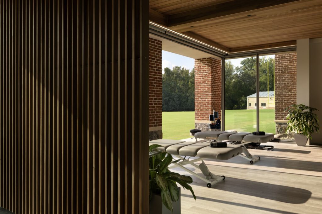 Warm wood-finished interior with massage tables, natural lighting, and scenic outdoor view, ideal for wellness or spa settings.